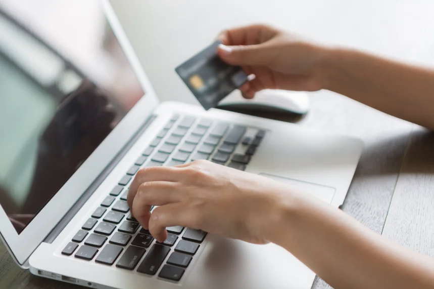 Person writing laptop with credit card
